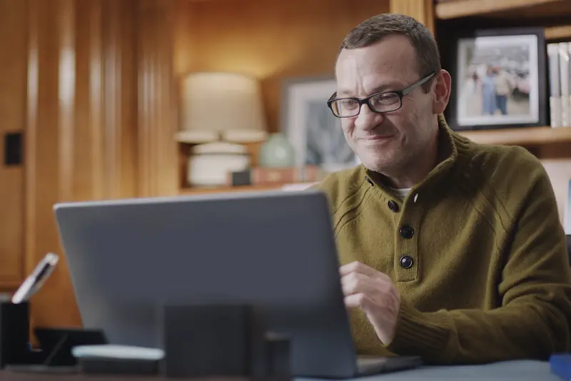 man smiling looking at a laptop screen